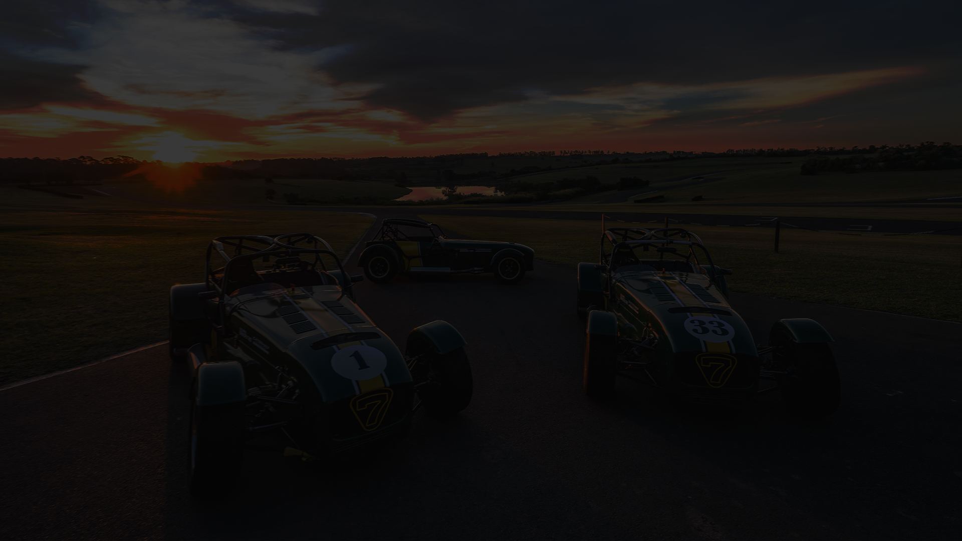 Caterhams da Scuderia Bandeiras na pista, ao entardecer